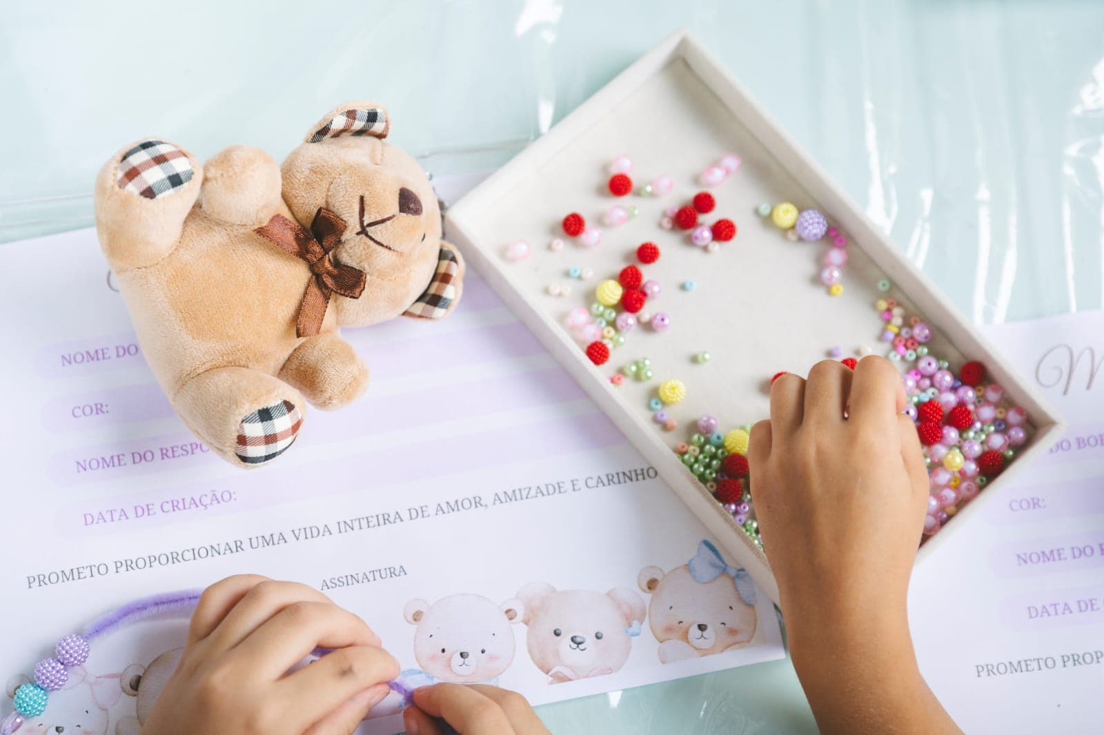mãos de criança escolhendo contas coloridas para montar um chaveiro artesanal